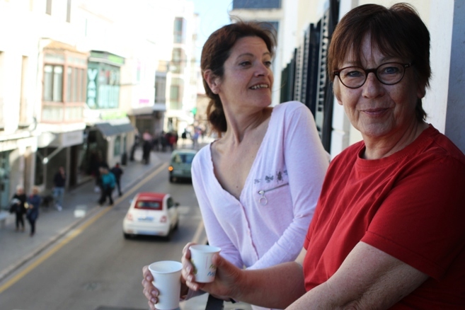 women standing on balcony drinking coffee