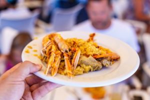 hand serving plate of seafood paella in a restaurant