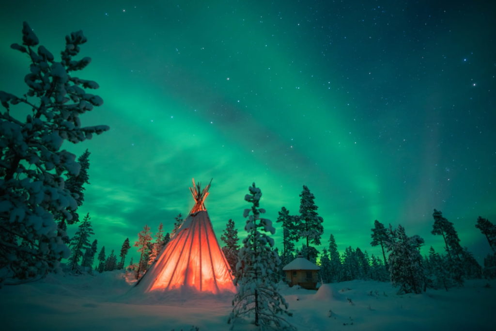 tent lit up at night under northern lights