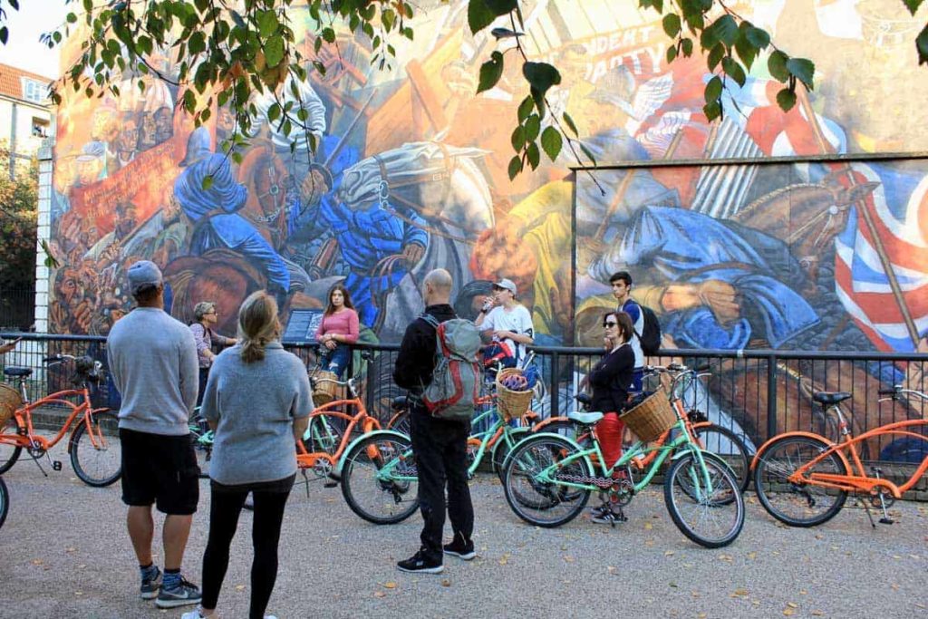 people on a bike tour in front of street art in east london