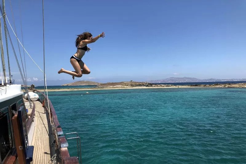 person jumping into the sea from a sailing boat in greece