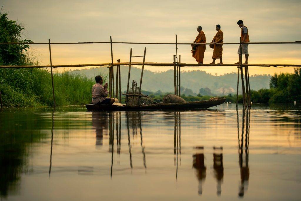 monks walking across a bridge in thailand