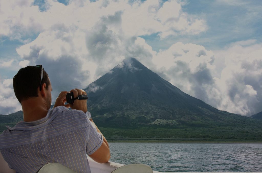 person taking a photo of arenal volcano in costa rica