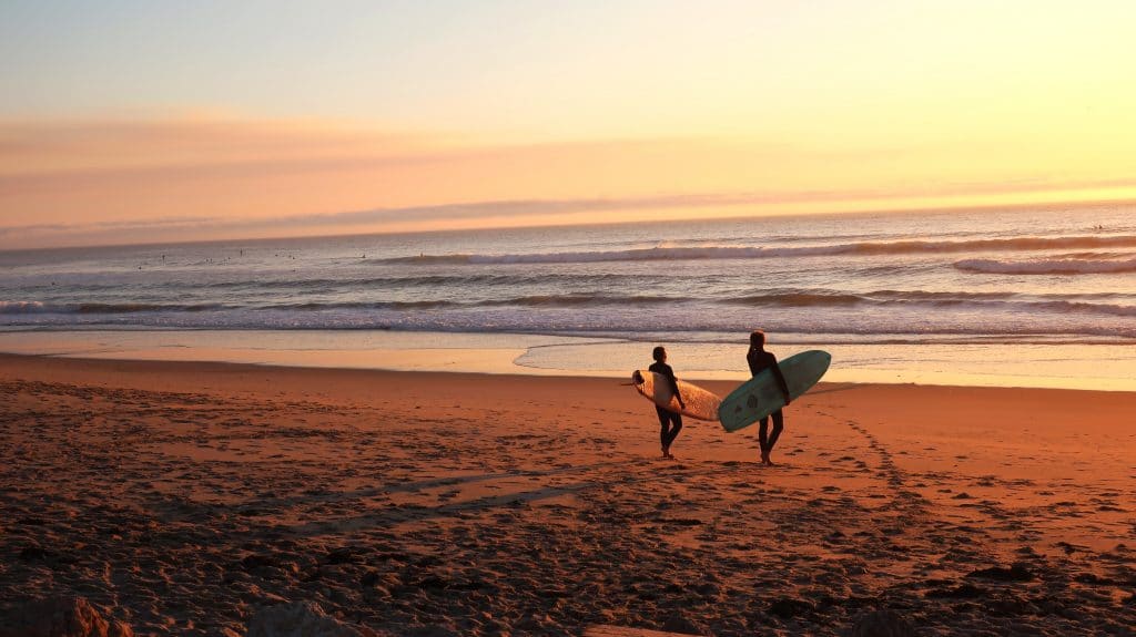 people with surfboards in portugal at sunset