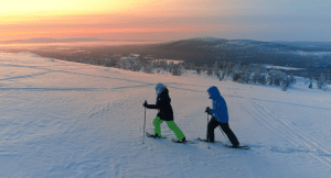 Couple snowshoeing in Lapland as the sun sets