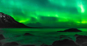 The northern lights floating in Norway over a lake