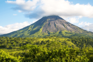 Arenal volcano surrounded by forest and clouds above
