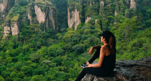 Woman sitting on a ledge looking over the forests of El Mirador in Mexico