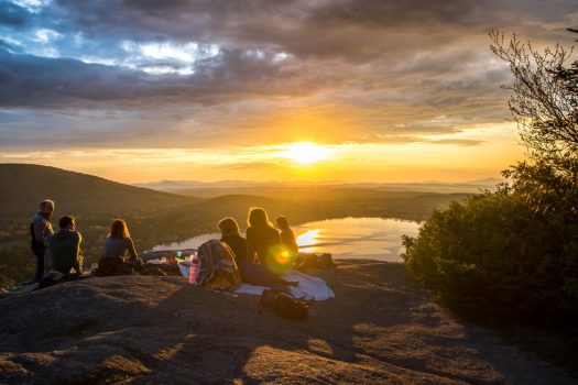 group of people enjoy sunset on mountain